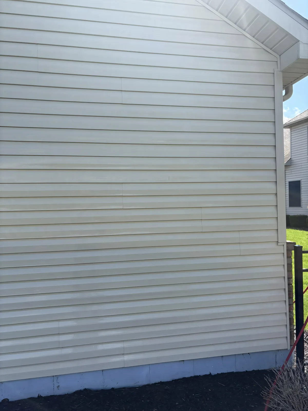 Clean cream vinyl siding after a Stoltz soft house wash