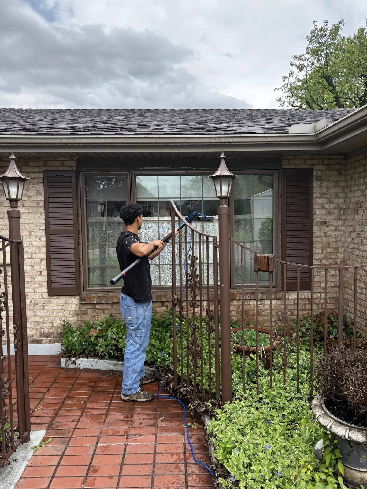 Stoltz tech soft-washing the exterior wall around windows on a brick home